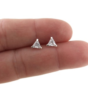May include: A pair of silver triangle stud earrings with clear cubic zirconia stones.