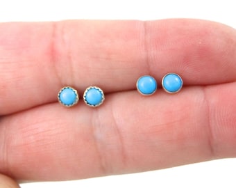 May include: A pair of silver stud earrings with turquoise stones. The earrings are small and round, with a silver setting.