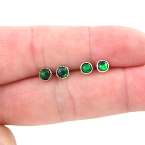 Puede incluir: Tres pares de pendientes de botón de plata con detalles de piedras preciosas verdes.