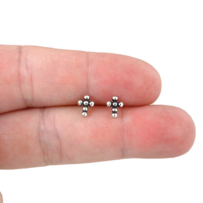 May include: A pair of silver cross stud earrings. Each earring is made of small silver beads in the shape of a cross.