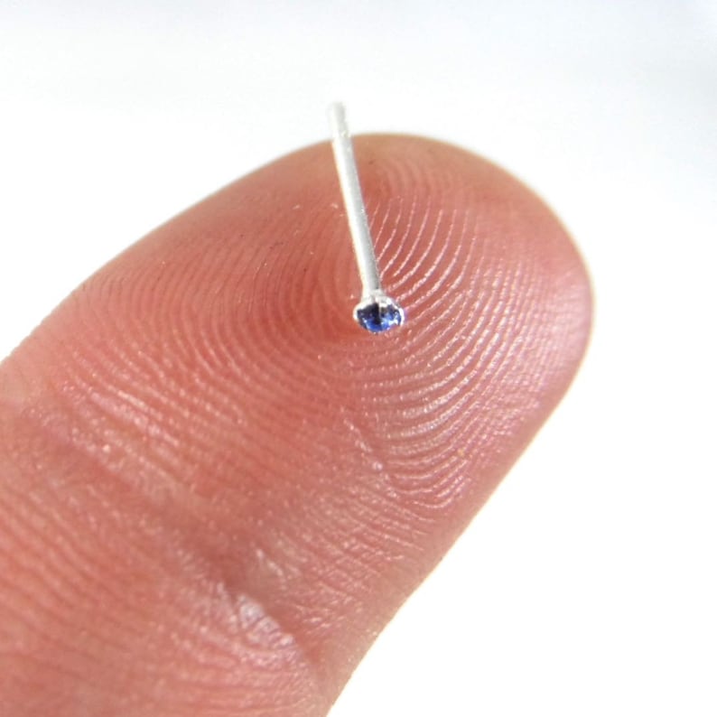 May include: A silver nose ring with a small blue gemstone.