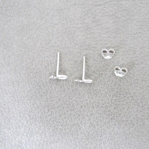 May include: A pair of silver butterfly stud earrings with a push-back closure.