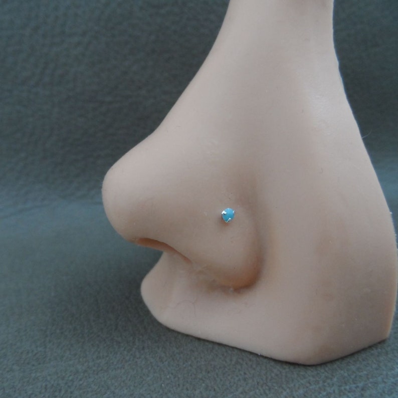 May include: A close-up of a light blue gemstone nose ring stud on a mannequin.