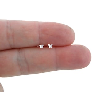 May include: A pair of small, silver butterfly stud earrings. Each earring features a delicate butterfly shape with detailed wings. The earrings are shown against a neutral background.