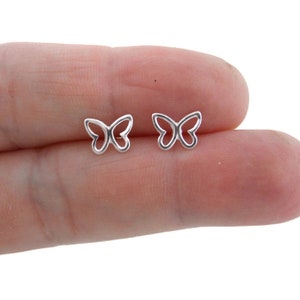 May include: A pair of silver butterfly stud earrings. The earrings are small and delicate, with a simple design.