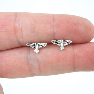 May include: A pair of silver bird stud earrings. The birds are in flight with their wings spread out.