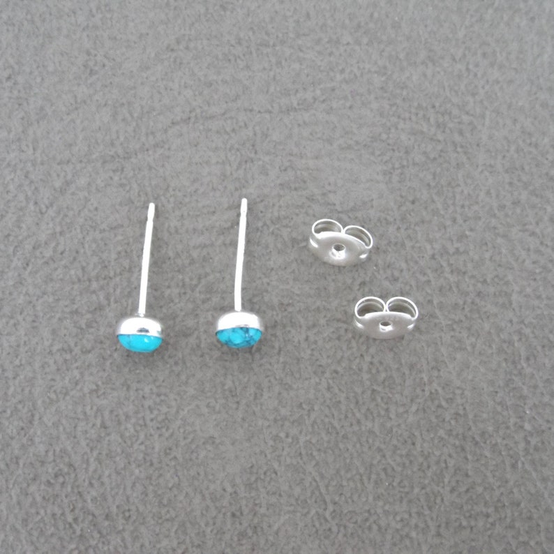 May include: A pair of silver stud earrings with turquoise stones. The earrings have a post and butterfly back.