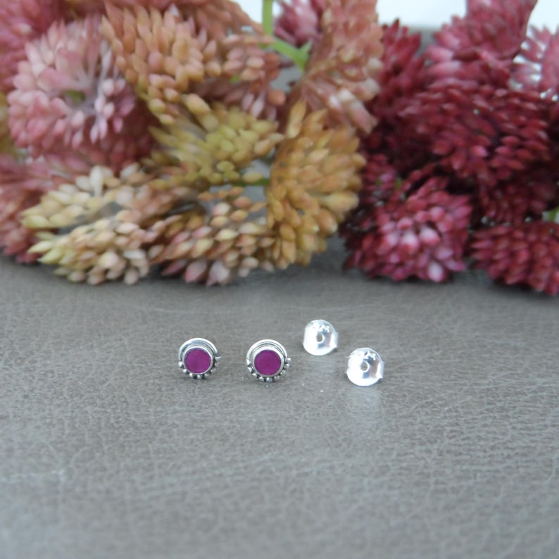 May include: A pair of silver stud earrings with small, round, pink gemstones set in the centre.