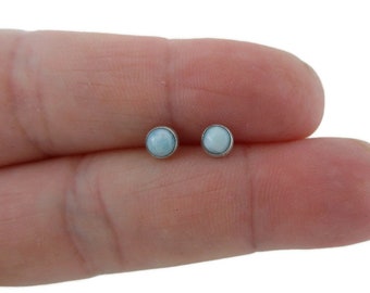May include: A pair of silver stud earrings with light blue round stones.