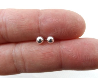 May include: A pair of small, silver ball stud earrings.