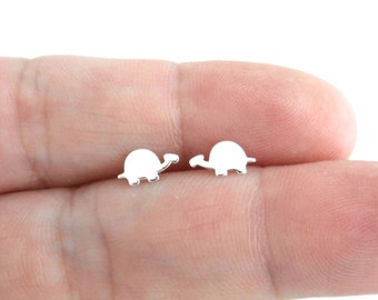 May include: A pair of silver turtle stud earrings. The turtles are facing each other and are about the size of a ten pence piece.