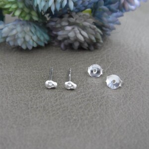 May include: A pair of silver skull stud earrings with a 925 stamp on the back.
