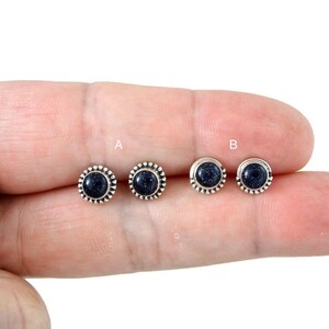 Pu&ograve; includere: Due paia di orecchini a bottone con una pietra centrale blu scuro macchiettata. Gli orecchini sono incastonati in un metallo color argento con un bordo perlato. Gli orecchini sono etichettati A e B.