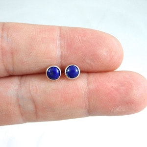 May include: A pair of silver stud earrings with round blue lapis lazuli gemstones.