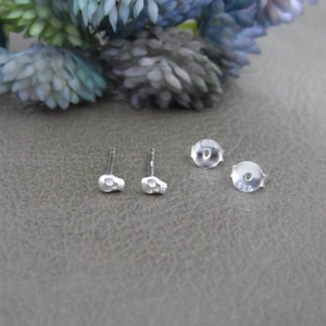 May include: A pair of silver skull stud earrings. The earrings are small and have a detailed skull design. The backs of the earrings are marked with the number 925.