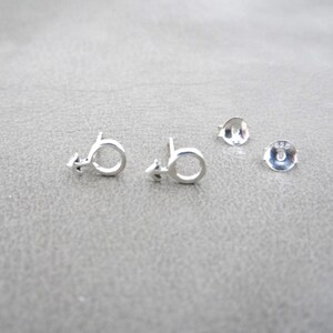 May include: A pair of silver earrings with a male symbol design. The earrings are marked with "925", indicating they are made of sterling silver.