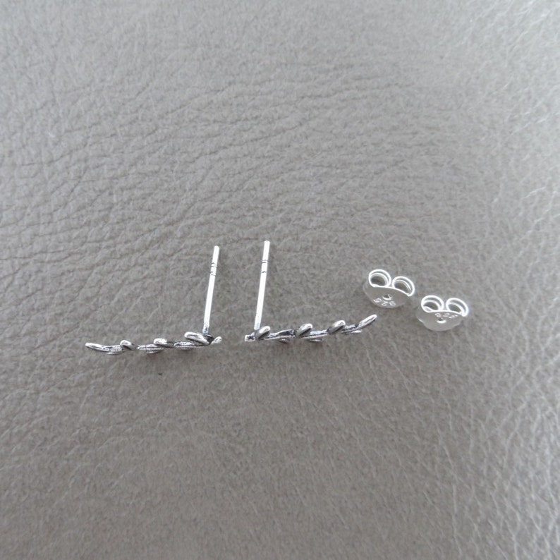 Puede incluir: Un par de pendientes de plata con un delicado dise&ntilde;o de hojas. Los pendientes se muestran con sus respaldos, que tambi&eacute;n son de plata.