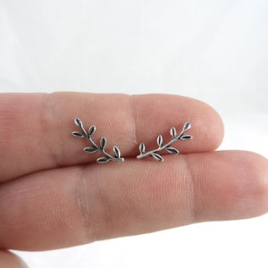 Puede incluir: Un par de pendientes de plata con forma de ramas delicadas con peque&ntilde;as hojas.