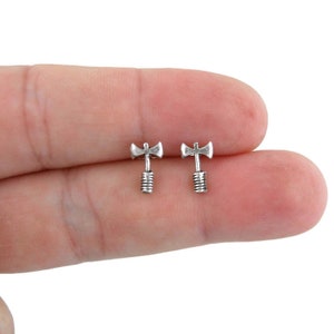 May include: A pair of silver axe-shaped stud earrings. The earrings are small and delicate, and they are perfect for adding a touch of edgy style to any outfit.