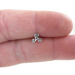 May include: A silver Celtic knot charm in the shape of a triquetra, a symbol of life, eternity, and the interconnectedness of all things.