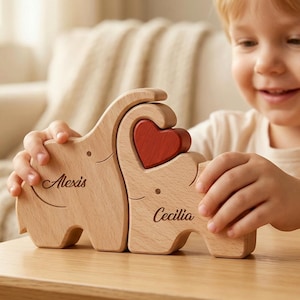 May include: Wooden elephant puzzle with a red heart insert. The puzzle is personalized with the names "Alexis" and "Cecilia" engraved on the sides. A charming and unique wooden toy for children.