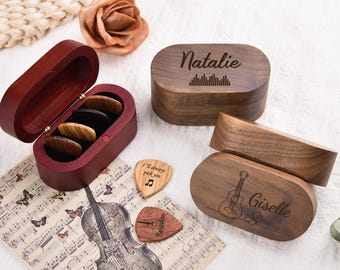 May include: Wooden guitar pick boxes and picks. One box is open, revealing picks. Two boxes are closed, one with the name "Natalie" and a sound wave design, the other with "Giselle" and a guitar illustration. Two picks have text.