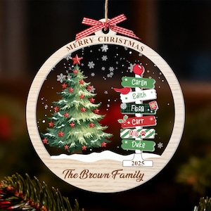 May include: Wooden Christmas ornament with a festive design. It features a Christmas tree, snowflakes, and a signpost with names. The ornament is personalized with "Merry Christmas" and "The Brown Family" and the year 2025.