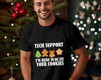Può includere: T-shirt nero con la scritta "TECH SUPPORT" sopra disegni di biscotti di pan di zenzero. Sotto c'è la frase "I'M HERE TO DELETE YOUR COOKIES". La maglietta è indossata da una persona.