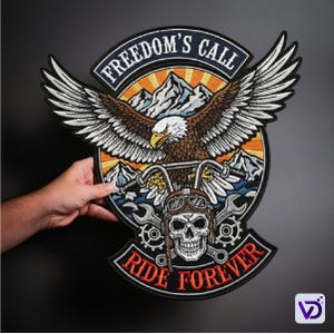 May include: Embroidered patch featuring a bald eagle with outstretched wings, mountains, and a motorcycle handlebar. The patch includes the text "FREEDOM'S CALL" and "RIDE FOREVER" in a bold font. The design incorporates brown, white, orange, and black colors.