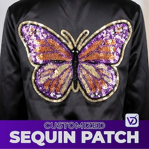 Puede incluir: Chaqueta de satén negro con un gran diseño de mariposa de lentejuelas en la espalda. La mariposa tiene lentejuelas moradas, naranjas y doradas, con un cuerpo de cuentas negro y un contorno dorado. El texto "CUSTOMIZED SEQUIN PATCH" está en la parte inferior.