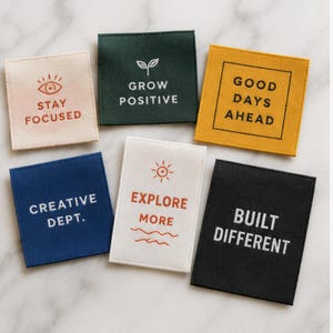 May include: Six square and rectangular fabric patches featuring various colors and text. The patches display the phrases STAY FOCUSED, GROW POSITIVE, GOOD DAYS AHEAD, CREATIVE DEPT., EXPLORE MORE, and BUILT DIFFERENT, accompanied by simple line art icons.