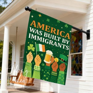 Könnte beinhalten: Eine grüne Flagge mit dem Text "AMERICA WAS BUILT BY IMMIGRANTS" in Weiß und Orange. Die Flagge zeigt Illustrationen von Händen, die ein Kleeblatt, eine irische Flagge, einen Bierkrug, eine Goldmünze und einen grünen Hut halten.