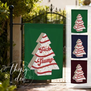 Könnte beinhalten: Eine rechteckige Gartenflagge mit einer stilisierten weißen Weihnachtsbaumgrafik, roten Wellenstreifen und dem Text "Fuck Trump" in roter Schreibschrift. Der Baum hat einen hellbraunen Rand und orangefarbene Sprenkel. Drei weitere Farbvarianten sind abgebildet.