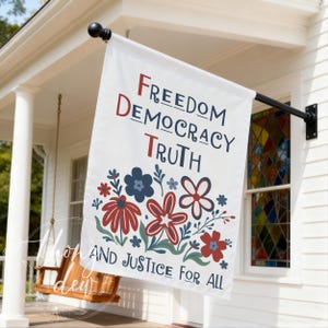May include: A white flag with the words "FREEDOM DEMOCRACY TRUTH" in navy and red lettering, with a floral design below. The words "AND JUSTICE FOR ALL" are at the bottom. The flag is hanging on a black rod.
