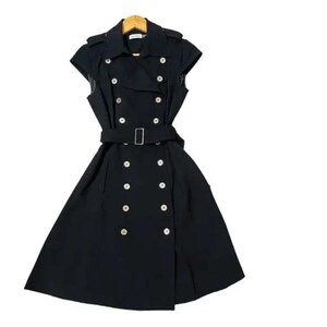 May include: A black sleeveless trench coat dress with a double-breasted front, featuring large silver buttons and a matching belt with a silver buckle. The dress has a classic trench coat design with a collar and shoulder epaulettes.