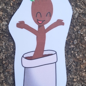 May include: A sticker featuring a cartoon plant character with a brown body, green leaves, and a smiling face. The plant is in a white pot with brown soil. The character has its arms open in a welcoming gesture.