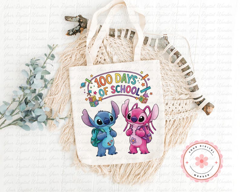 Op de afbeelding: Een witte draagtas met de tekst "100 Days of School" en stripfiguren. De tas heeft een blauw en roze buitenaards wezen met rugzakken. Het ontwerp bevat kleurrijke sterren, potloden en een planeet.