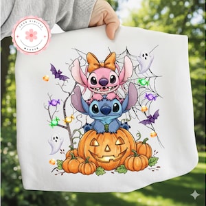 Può includere: Grafica bianca a tema Halloween con i personaggi Stitch e Angel sopra una zucca intagliata. Il design include pipistrelli, fantasmi, caramelle e una ragnatela. L'immagine è tenuta da una persona.