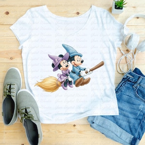 K&ouml;nnte beinhalten: Wei&szlig;es T-Shirt mit einer Cartoon-Illustration von Mickey und Minnie Mouse als Zauberer auf einem Besen. Das Bild zeigt graue Turnschuhe, blaue Jeansshorts und wei&szlig;e Kopfh&ouml;rer. Auf Holz gelegt.