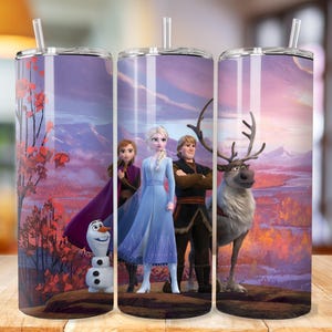 May include: Three stainless steel tumblers with a Frozen theme. The tumblers feature a purple, pink, and blue sunset background with Elsa, Anna, Kristoff, and Olaf. A reindeer is also featured in the image.