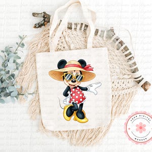 May include: A white tote bag featuring a cartoon Minnie Mouse character wearing sunglasses, a straw hat, and a red polka dot dress. The bag has cream-colored handles and a floral logo in the bottom right corner.