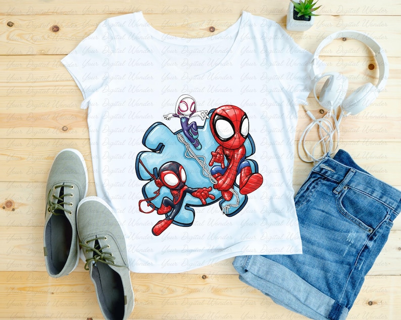 May include: White t-shirt with a vibrant graphic of Spider-Man and two other Spider-Verse characters. The shirt is styled with denim shorts, grey trainers, and white headphones on a wooden surface.