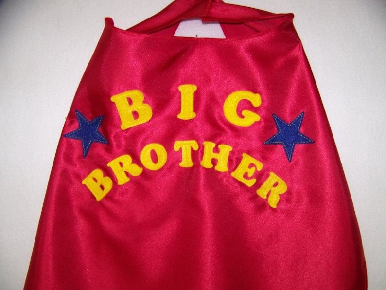 May include: Red satin cape with yellow embroidered text "BIG BROTHER" and two blue stars.