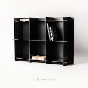 Può includere: Una libreria in metallo nero con più scomparti. Due libri sono visibili sugli scaffali e il testo "FORMAGNIFICA" è in basso. La libreria ha un design moderno.