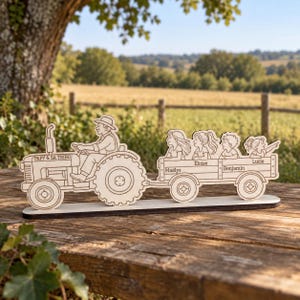 Può includere: Un pezzo decorativo in legno tagliato al laser raffigurante un trattore guidato da una persona, che traina un rimorchio con quattro bambini. Il trattore è inciso con il testo "PAPY & SA TRIBU" e il rimorchio riporta i nomi "Maëlys", "Éloise", "Benjamin" e "Lucie".
