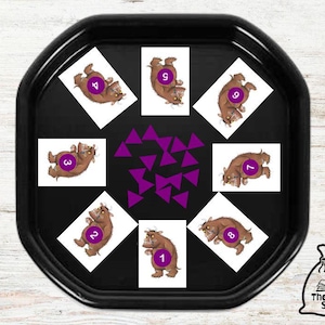 Könnte beinhalten: Ein schwarzes Tablett aus Kunststoff mit neun Karten, die Illustrationen eines braunen Tieres mit den Zahlen 1 bis 9 zeigen. Die Karten sind in einem Kreis um eine Streuung von violetten Dreiecksformen angeordnet.