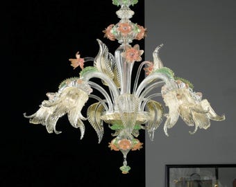 Può includere: Un lampadario in vetro trasparente con decorazioni floreali e a foglie. Il lampadario presenta fiori e foglie color pesca e verdi. L'apparecchio è sospeso a una catena e ha più punti luce.
