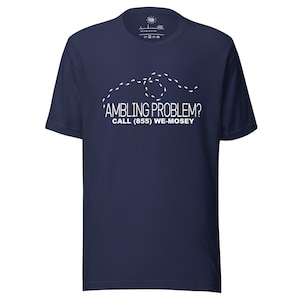 Peut inclure: T-shirt bleu marine avec texte blanc et un motif en pointillés. Le texte indique : "'AMBLING PROBLEM? CALL (855) WE-MOSEY". Le t-shirt a un col rond et des manches courtes.