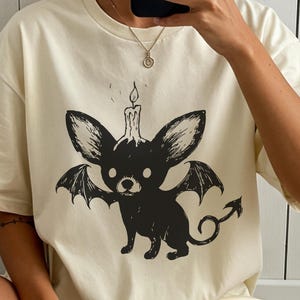 ハロウィンチワワ悪魔シャツ - 羽、ろうそく、コウモリをあしらったゴシックホラーデザイン。不気味な季節にぴったりの恐ろしいインクリノカットチワワTシャツ