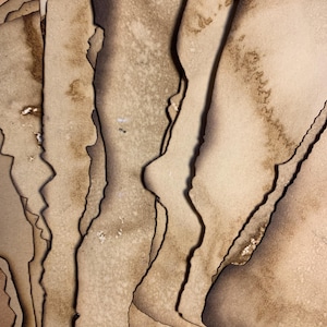 Op de afbeelding: Een stapel oud, bruin papier met ongelijke randen en bruine vlekken. Het papier is gelaagd en licht gekruld.